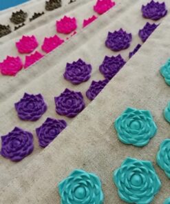 close-up of linen acupressure mat color options with turquoise, purple, pink, and brown pressure points across natural fabric