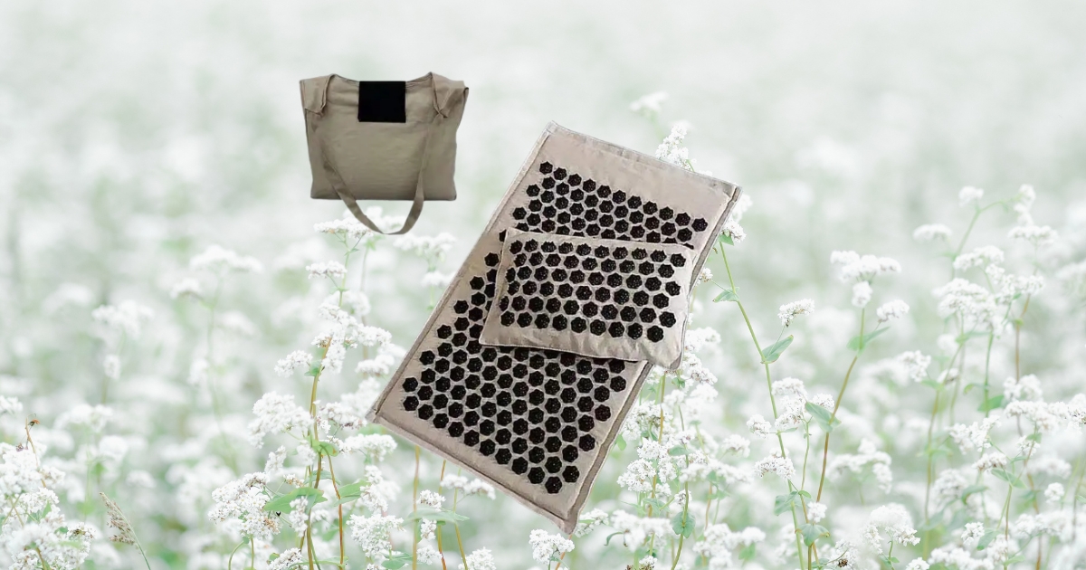 lifestyle image of a linen acupressure mat with pillow and carry bag set against soft white flowers for calm wellness inspiration